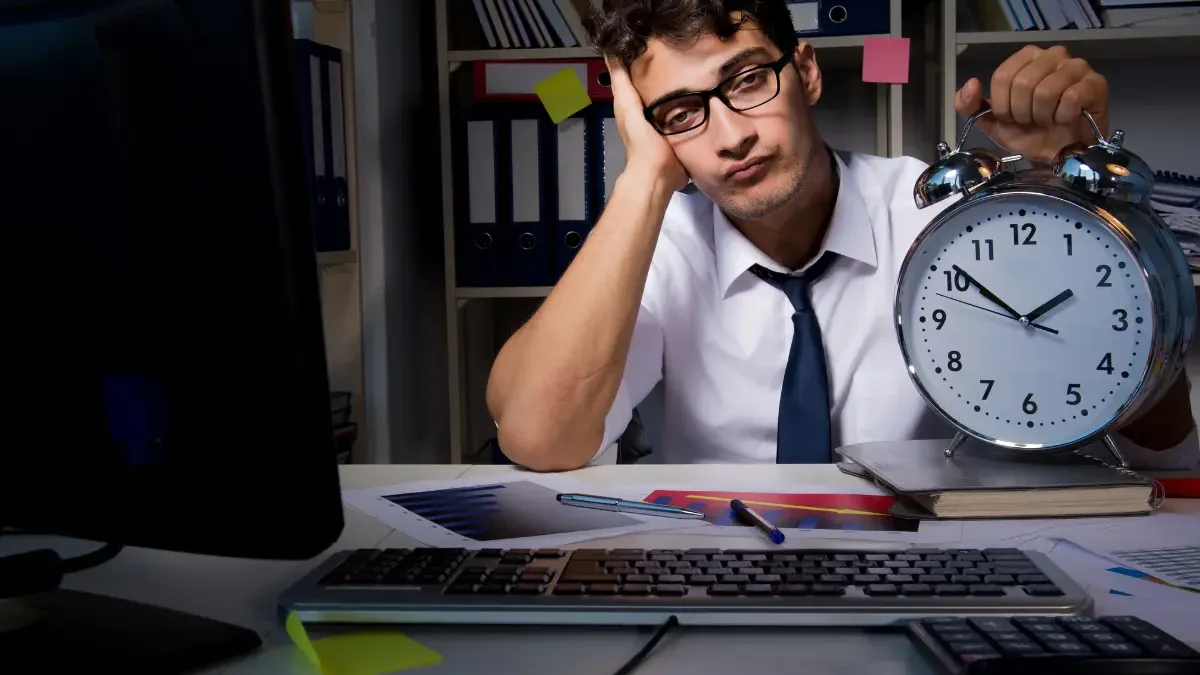 Trabalhador a fazer horas extraordinárias ao fim do dia no escritório, exemplo da calculadora de horas extraordinárias