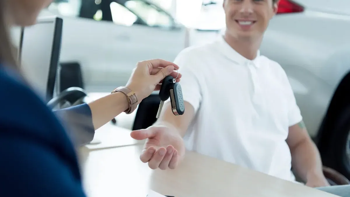 Cliente a receber as chaves de um carro novo num stand, exemplo do simulador de crédito automóvel